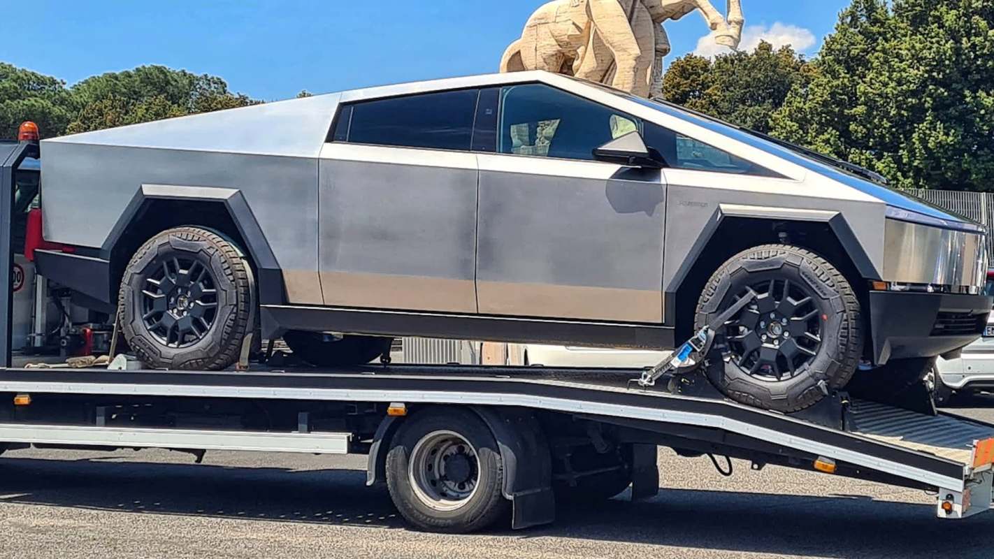 A futuristic, angular pickup truck on a flatbed tow truck.