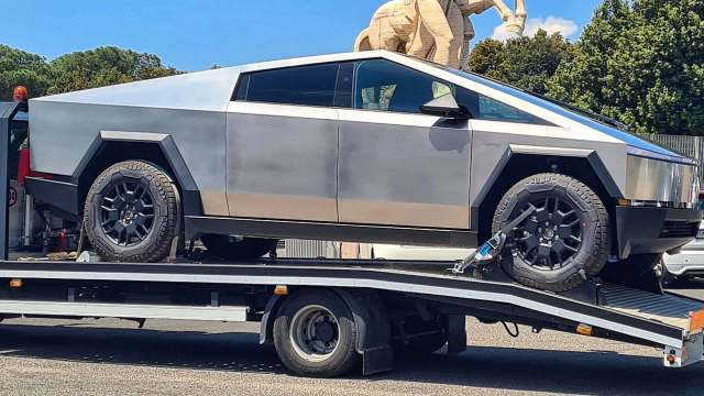 A futuristic, angular pickup truck on a flatbed tow truck.