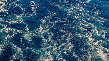 A close-up view of blue ocean water with white foamy waves and ripples.
