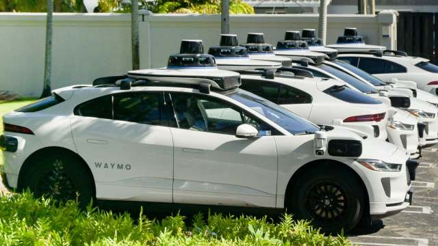 A row of Waymo's white autonomous electric vehicles parked outside.