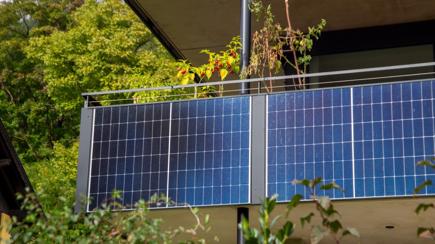 A balcony with solar panels next to potted plants.