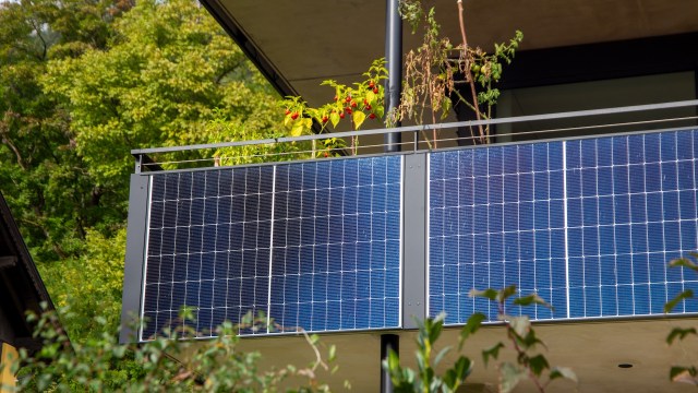 A balcony with solar panels next to potted plants.