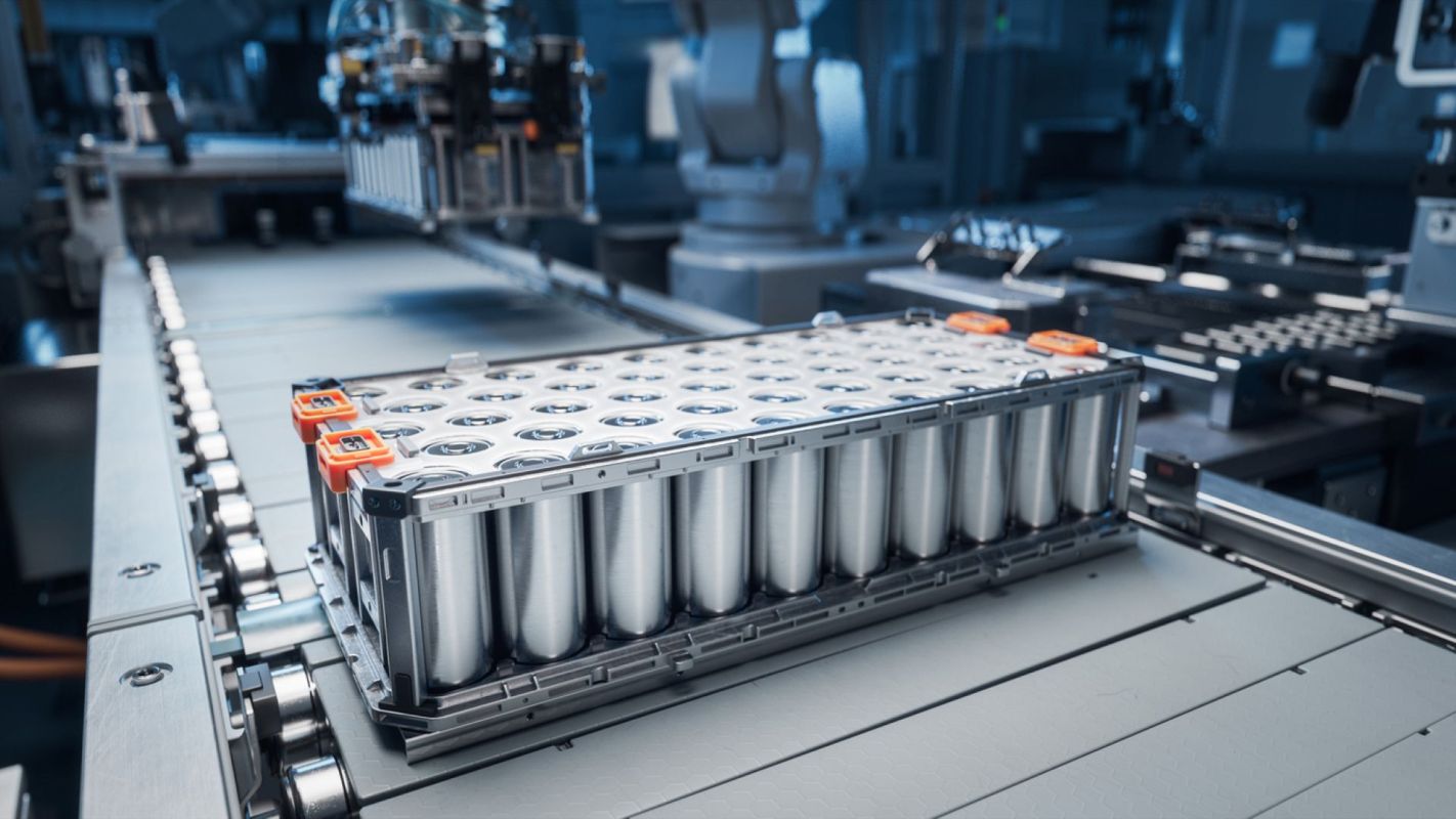 A close-up of an electric vehicle battery pack on an assembly line in a modern manufacturing facility.