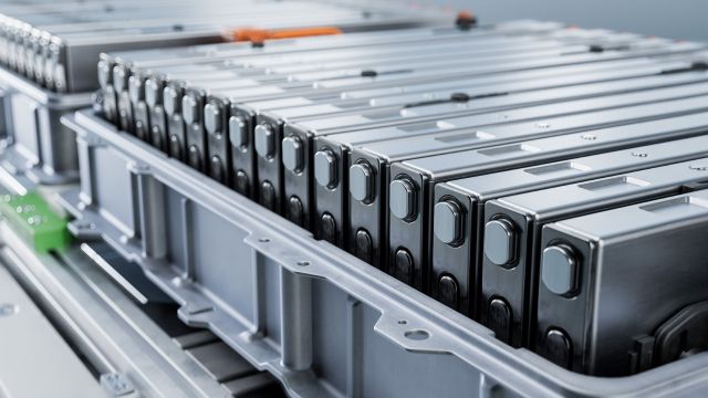 A close-up of stacked battery modules in a gray container, highlighting their metallic finish and design.