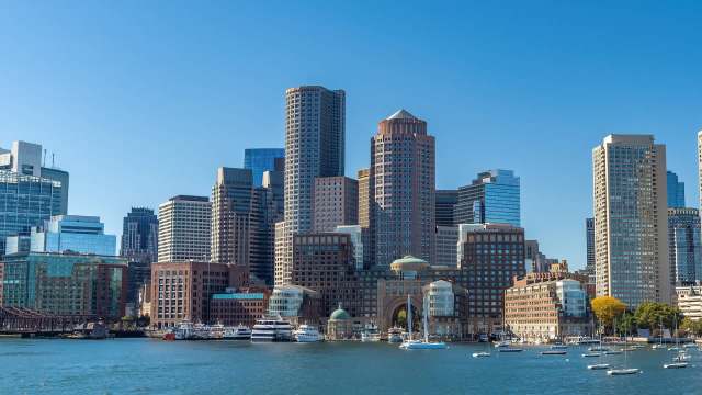 The Boston skyline along the waterfront with boats in the harbor.