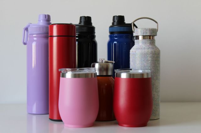 A group of colorful water bottles and travel mugs arranged on a white surface.