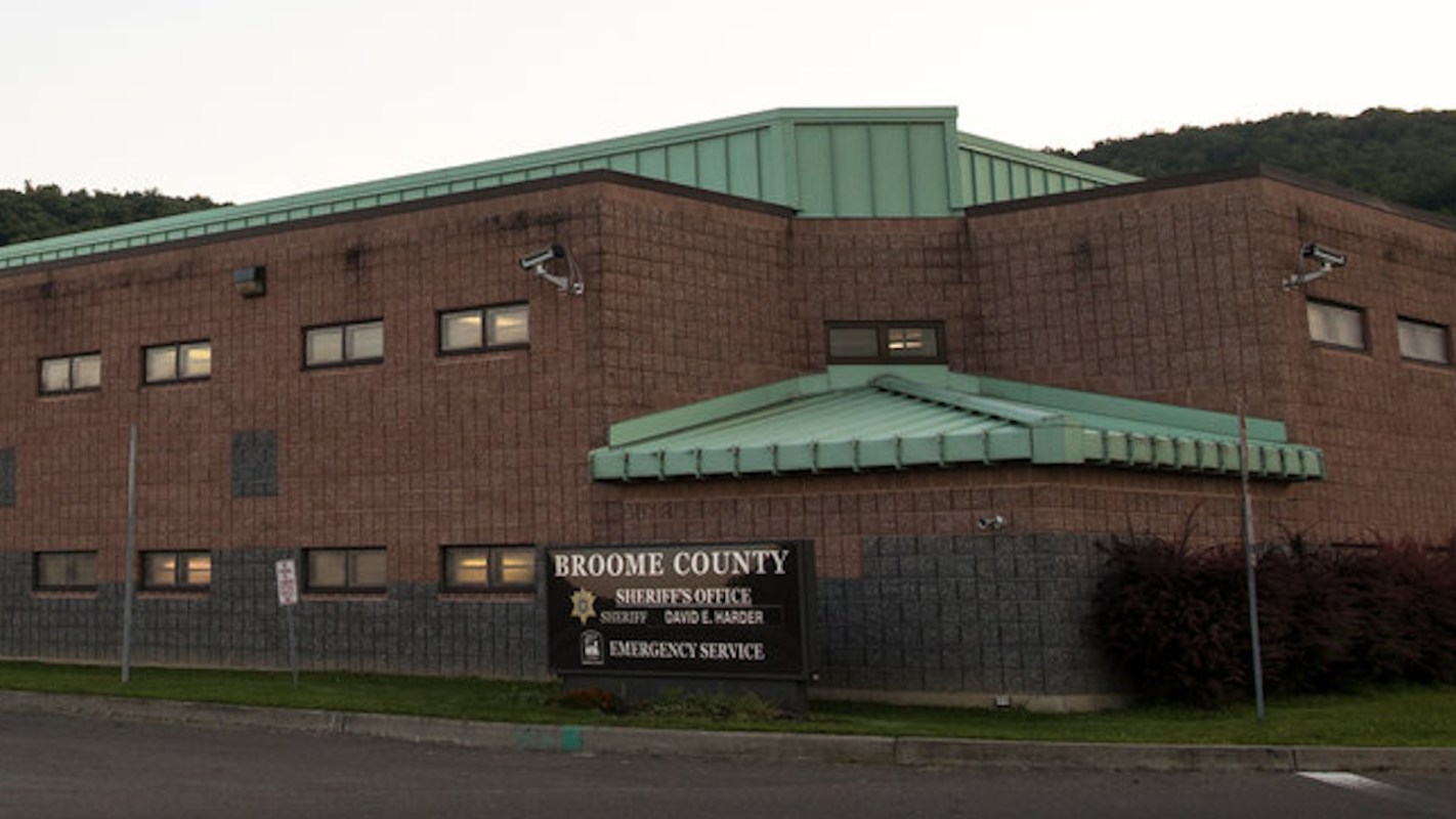 A brick building with a green roof, featuring a sign for the Broome County Sheriff's Office and Emergency Service.