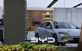 A silver BYD Seal car displayed in a showroom with plants and modern decor in the background.