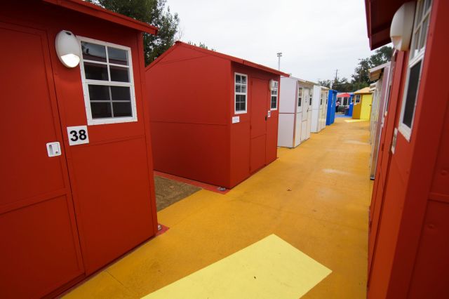 A row of colorful tiny homes with a bright yellow pathway on an overcast day.