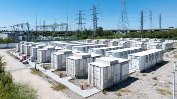 A solar energy storage facility with white containers and high-power transmission lines in the background.