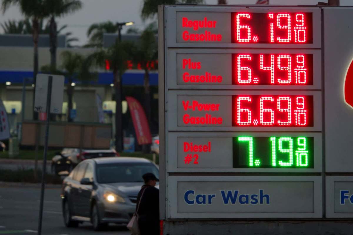 A gas station sign displaying fuel prices for regular, plus, V-Power gasoline, and diesel at dusk.