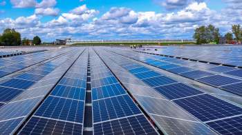 A large solar panel array under a partly cloudy sky.