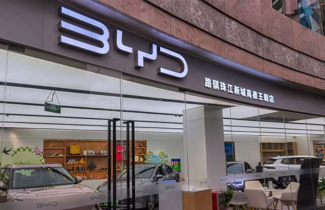A modern car dealership displaying BYD vehicles and promotional materials through a glass front.