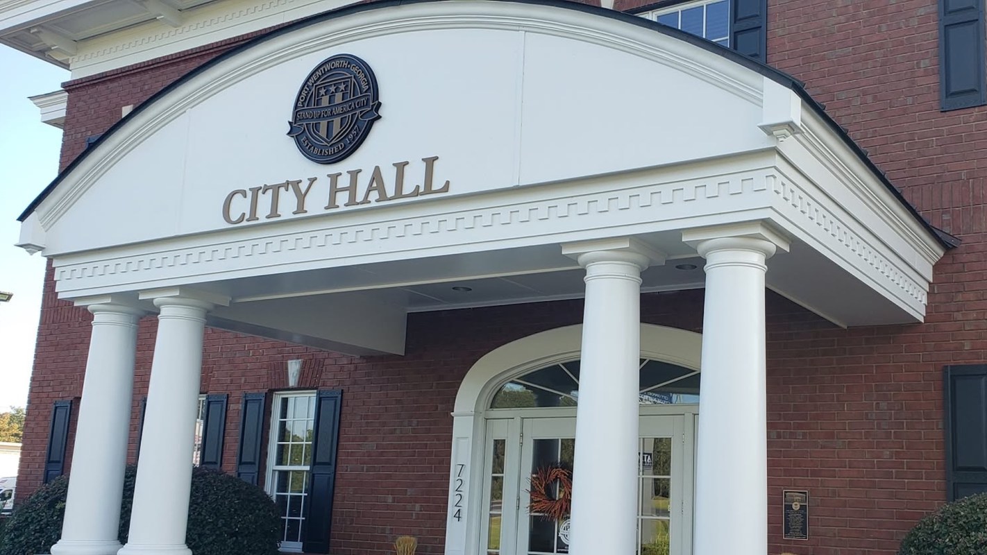 A city hall building with white pillars and a red brick facade.