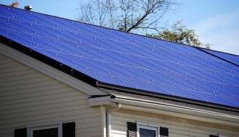 A rooftop covered with blue solar panels under a clear blue sky.