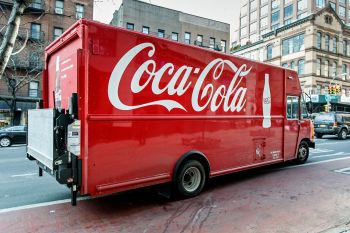 A delivery truck with a prominent Coca-Cola logo parked on a city street.