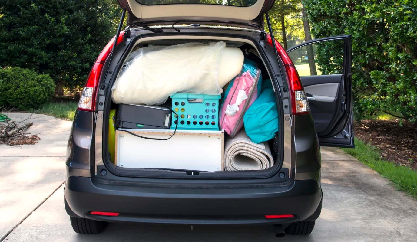 A car trunk filled with various items including bags, blankets, and a storage bin.
