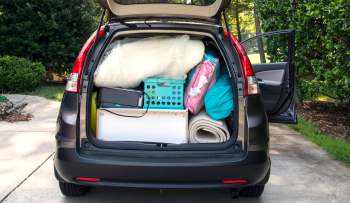 A car trunk filled with various items including bags, blankets, and a storage bin.