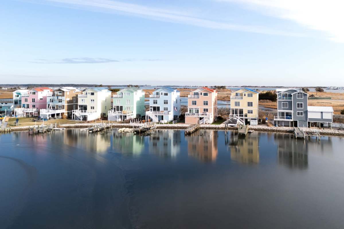 Colorful waterfront houses with docks reflecting in the water on a clear day.