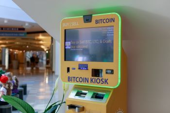 A Bitcoin kiosk in mall, displaying cryptocurrency purchasing options on a touchscreen.