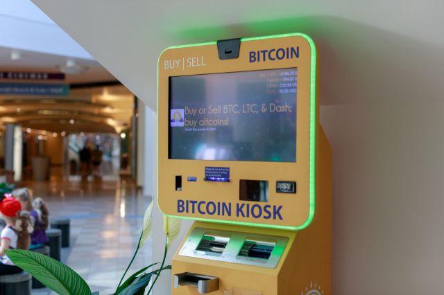 A Bitcoin kiosk in mall, displaying cryptocurrency purchasing options on a touchscreen.