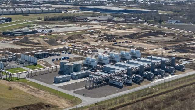 An industrial facility with large structures and tanks under development, surrounded by construction and parking areas.