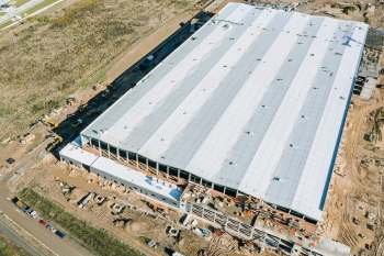 Aerial view of a large industrial building under construction with various machinery and materials around it.