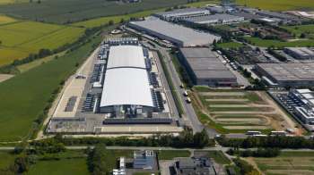 An aerial view of industrial warehouses, including a data center, surrounded by green fields and farmland.