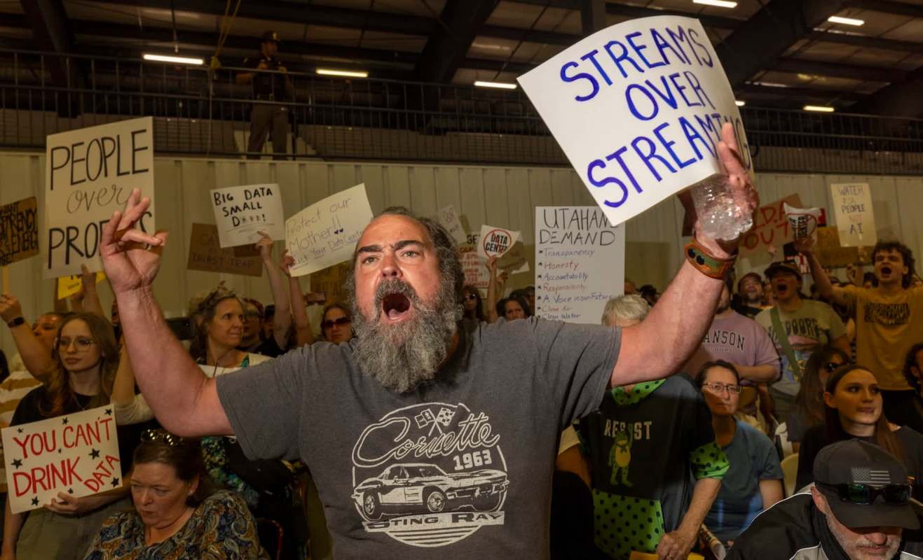 A protestor shouts with a sign demanding data center regulations.