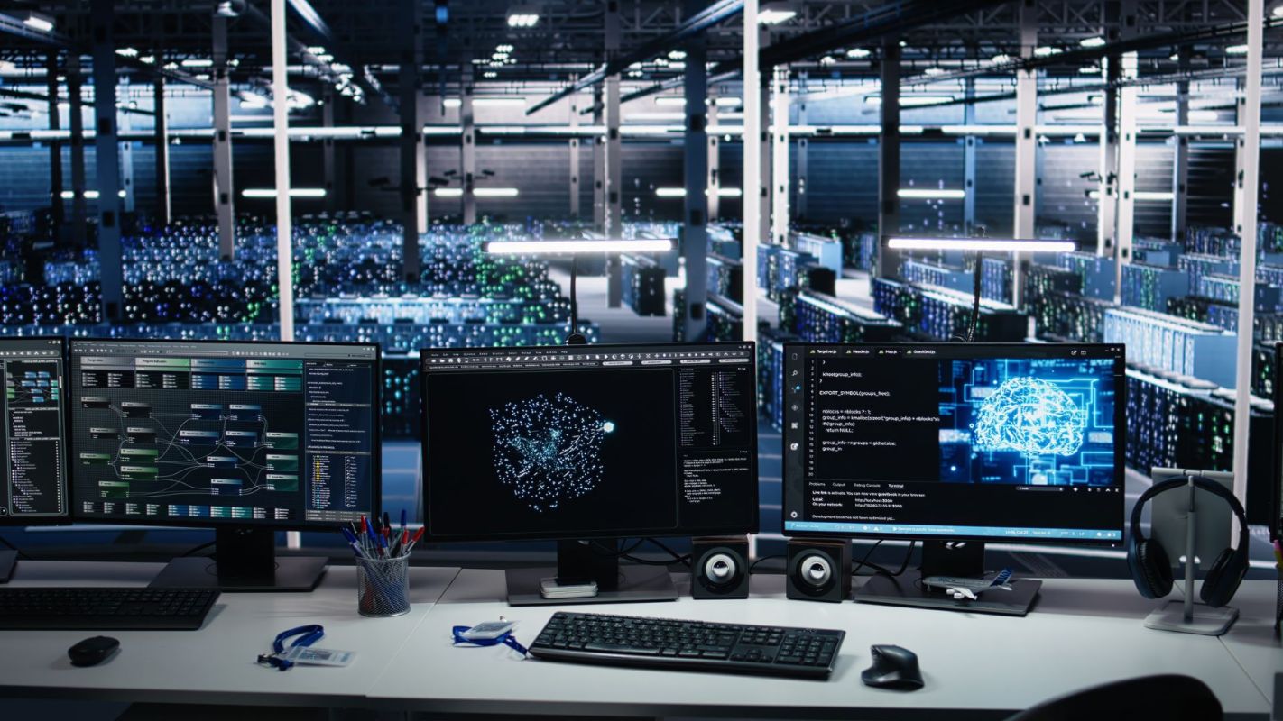 A modern workspace with multiple monitors displaying data visualizations in a data center environment.