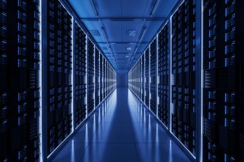 A data center corridor lined with illuminated server racks on either side.
