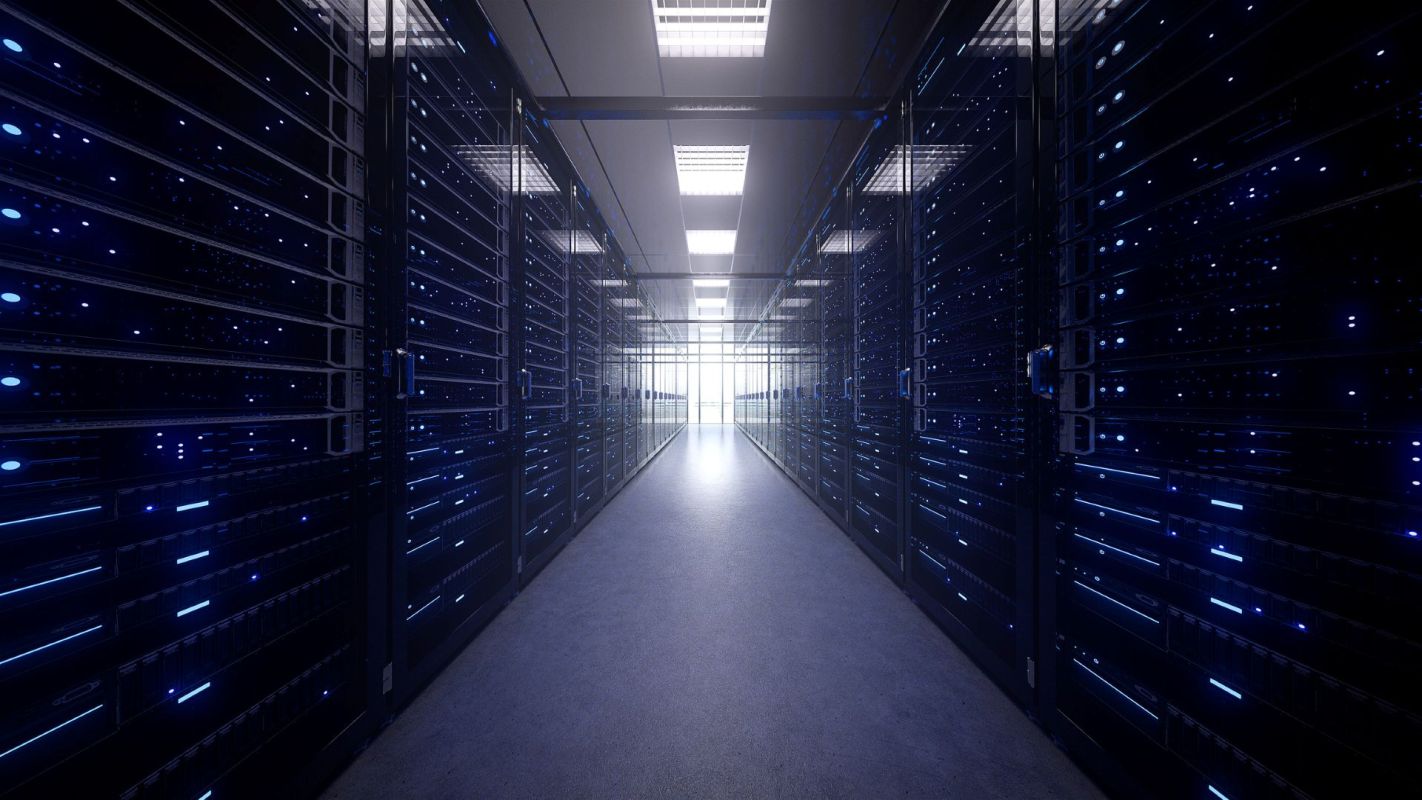 A data center corridor's server racks illuminated by blue lights.