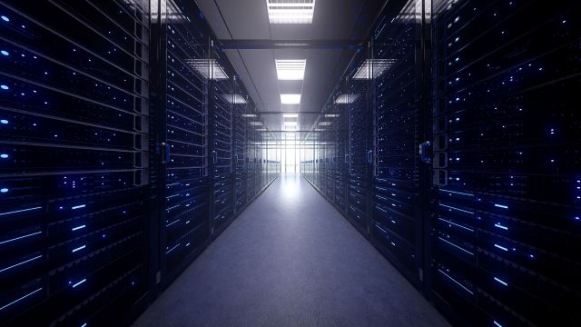 A data center corridor's server racks illuminated by blue lights.
