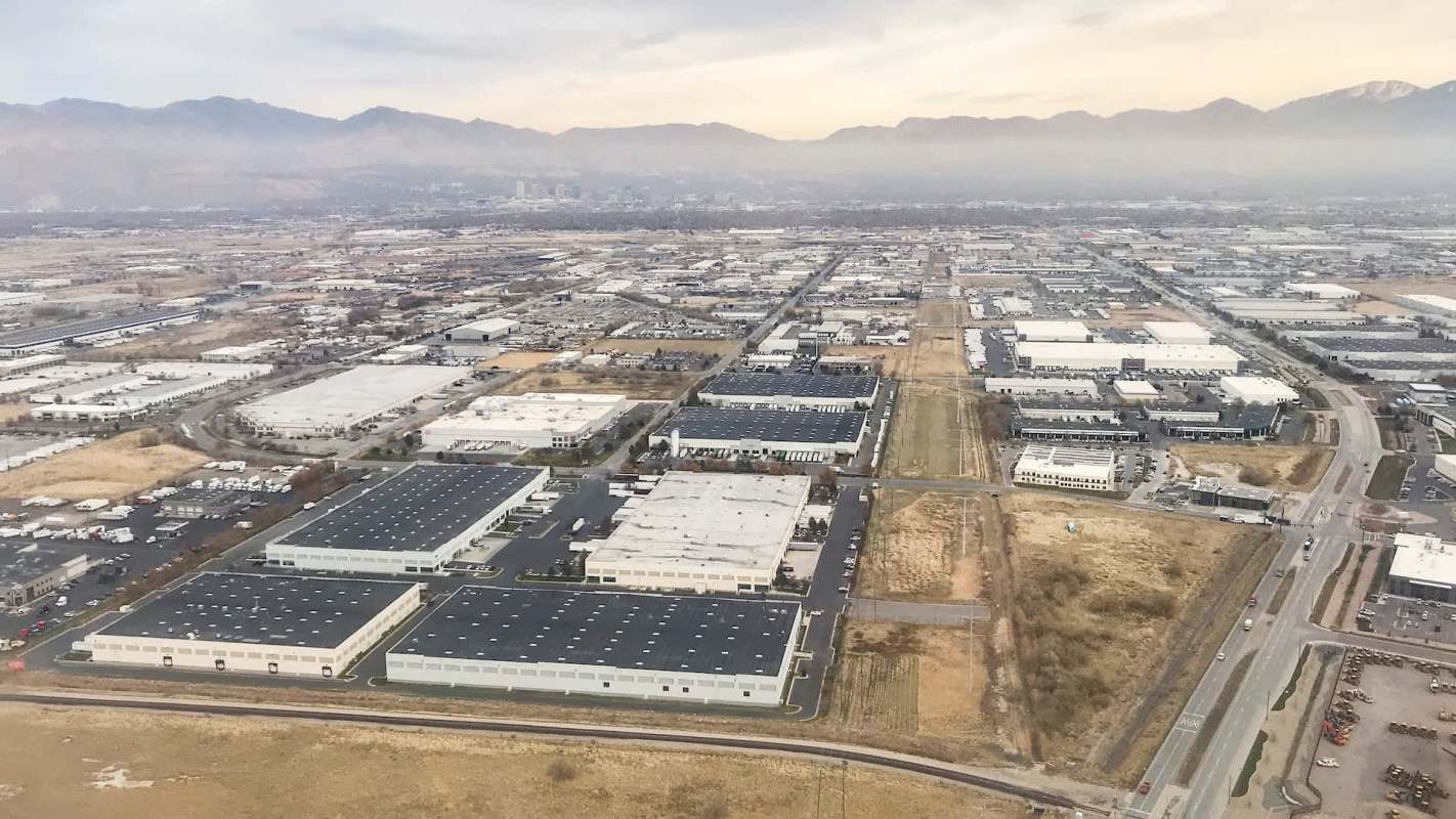 Aerial view of a sprawling industrial area with warehouses and mountains in the background.