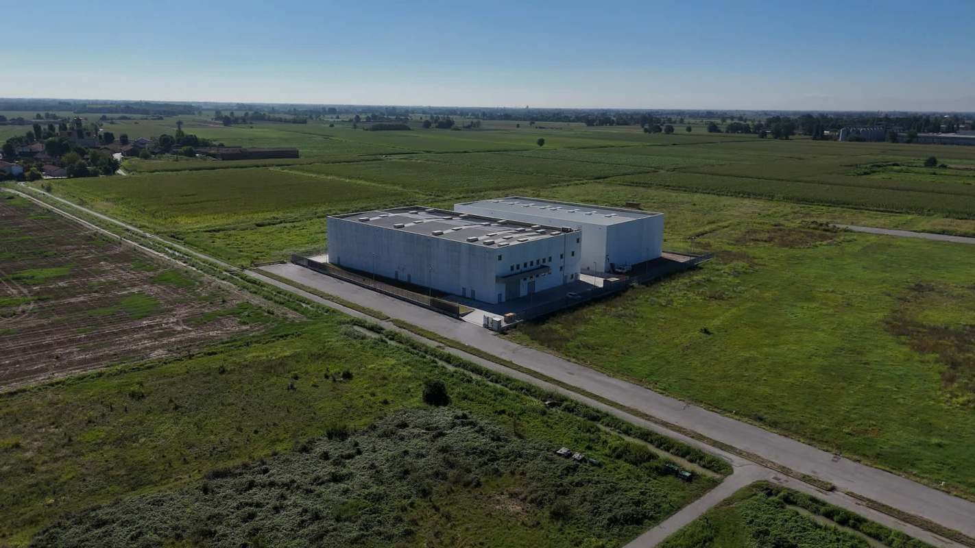 Aerial view of two large data centers surrounded by expansive green fields.