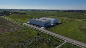 Aerial view of two large data centers surrounded by expansive green fields.