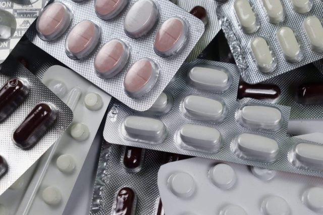 A collection of various blister packs containing different colored pills and capsules.