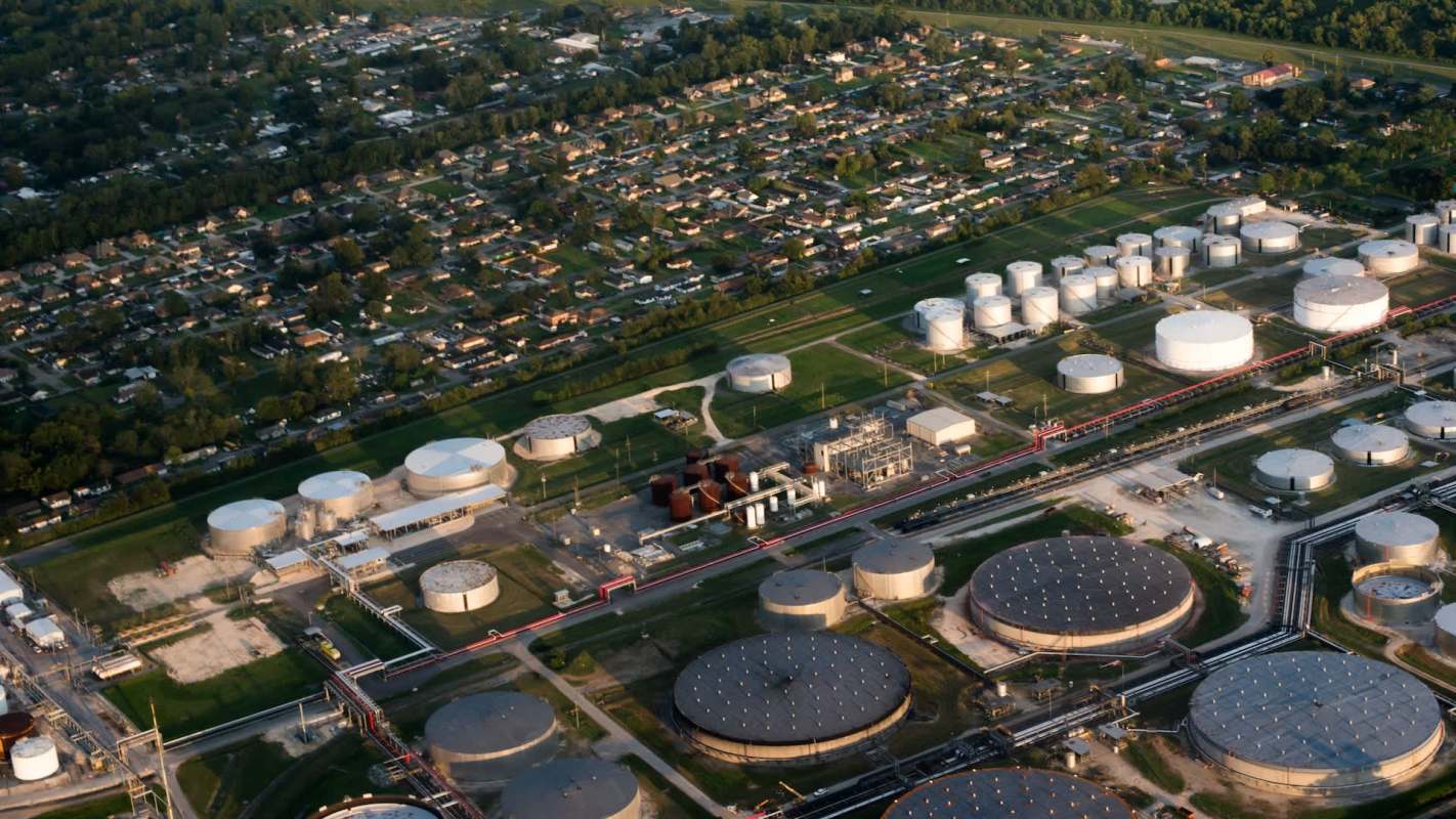 An aerial view of an industrial facility with storage tanks adjacent to a residential neighborhood.