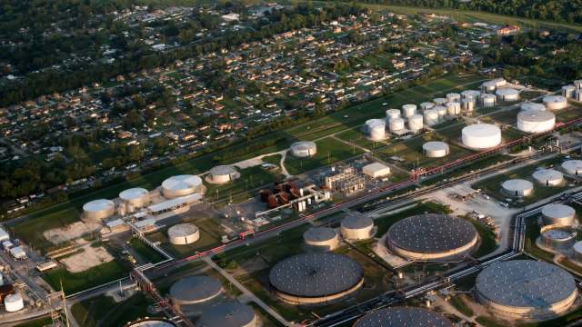 An aerial view of an industrial facility with storage tanks adjacent to a residential neighborhood.