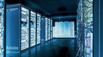 A dimly lit data center filled with server racks and tangled cables against a blue-toned backdrop.