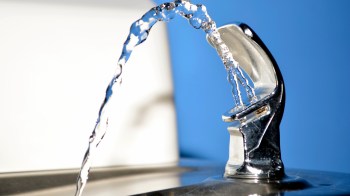 A close-up of a water fountain spouting clear water against a blue background.