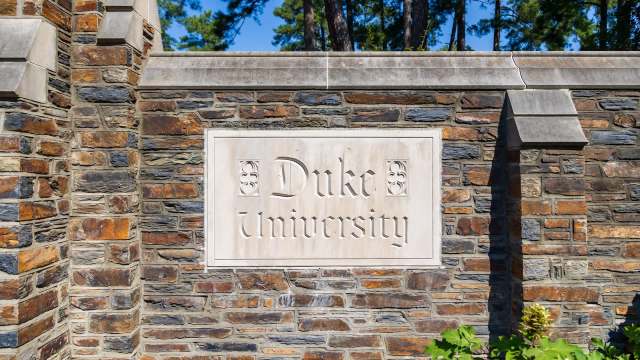 A stone wall featuring a prominent sign that reads "Duke University" in elegant lettering.