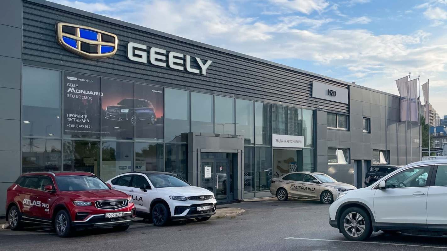 A Geely dealership with several cars parked outside and a promotional banner on the building.