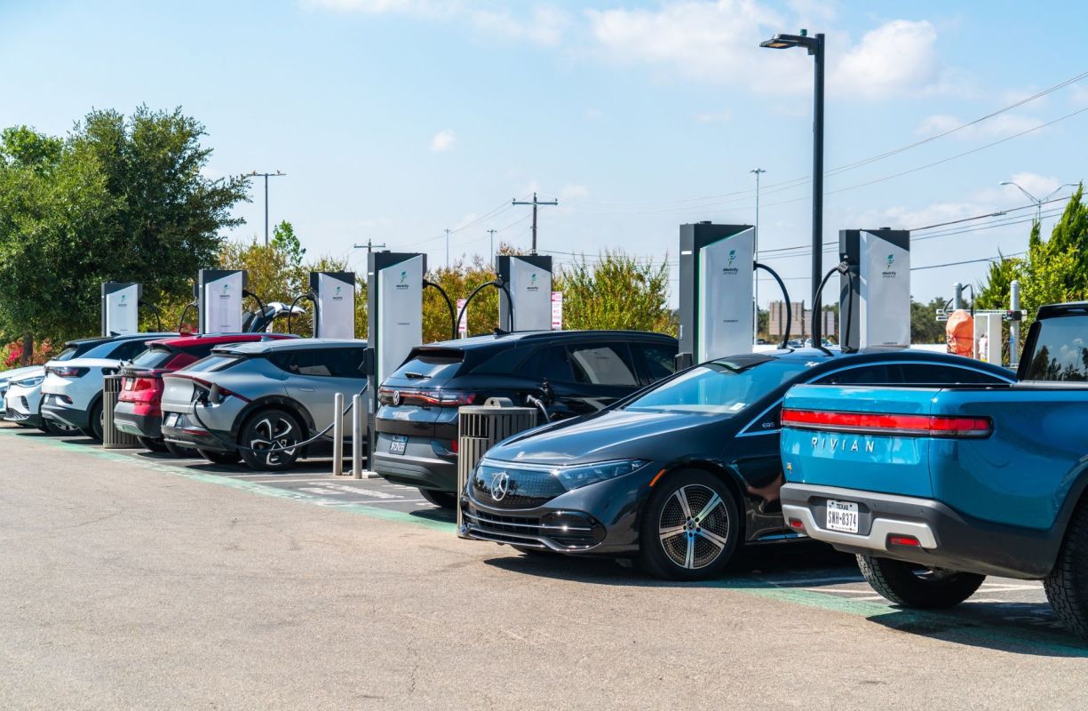 A row of electric vehicles at charging stations.