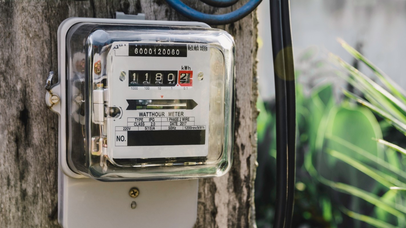 An electric watt-hour meter mounted on a wooden post.