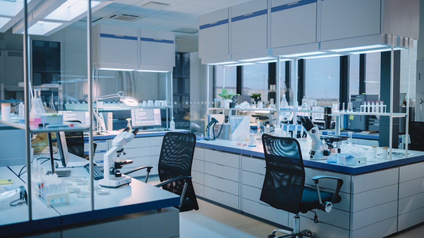 A modern laboratory equipped with microscopes, glassware, and computer workstations under bright lighting.