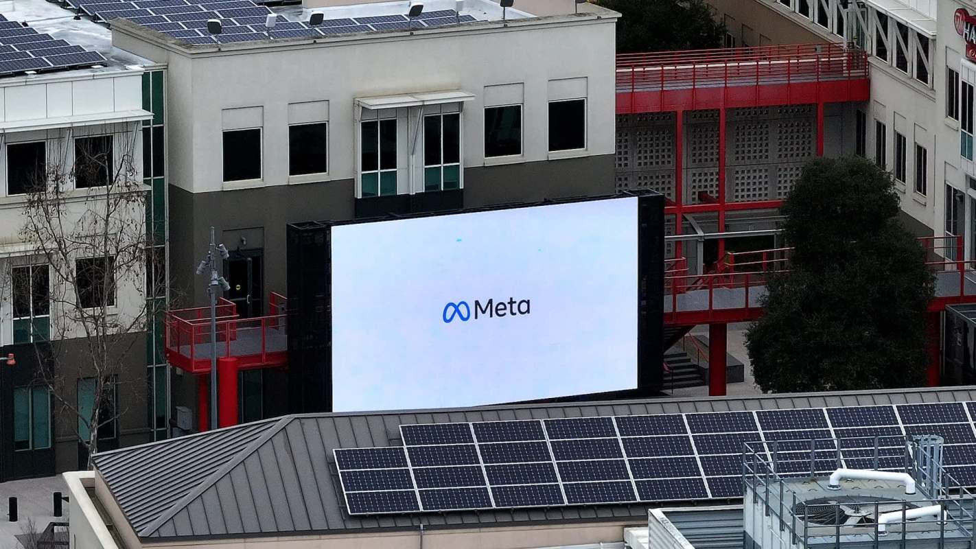 A large outdoor screen displaying the Meta logo on a building with solar panels in the foreground.