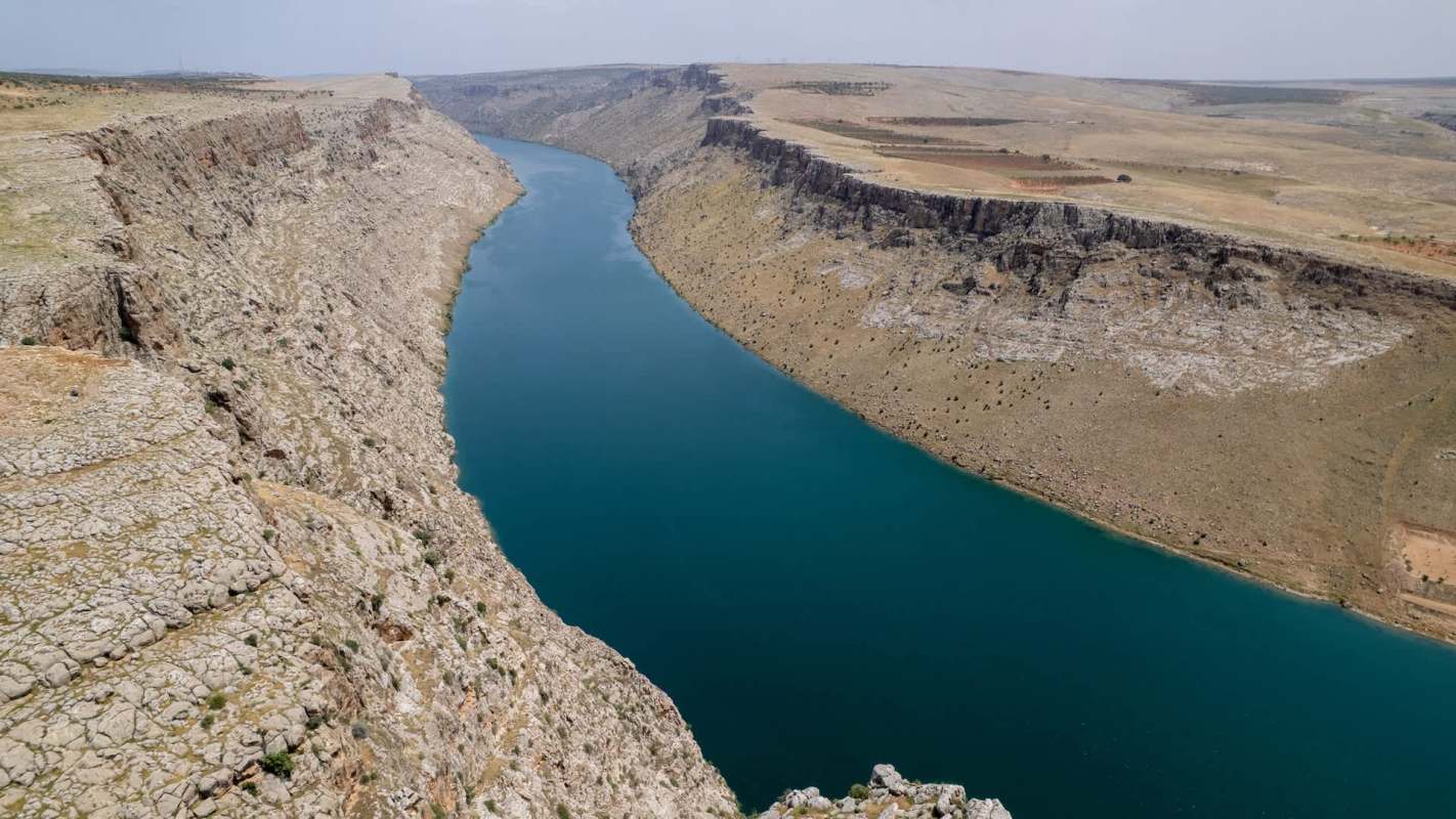 A winding river flows through a rocky canyon landscape under a clear sky.