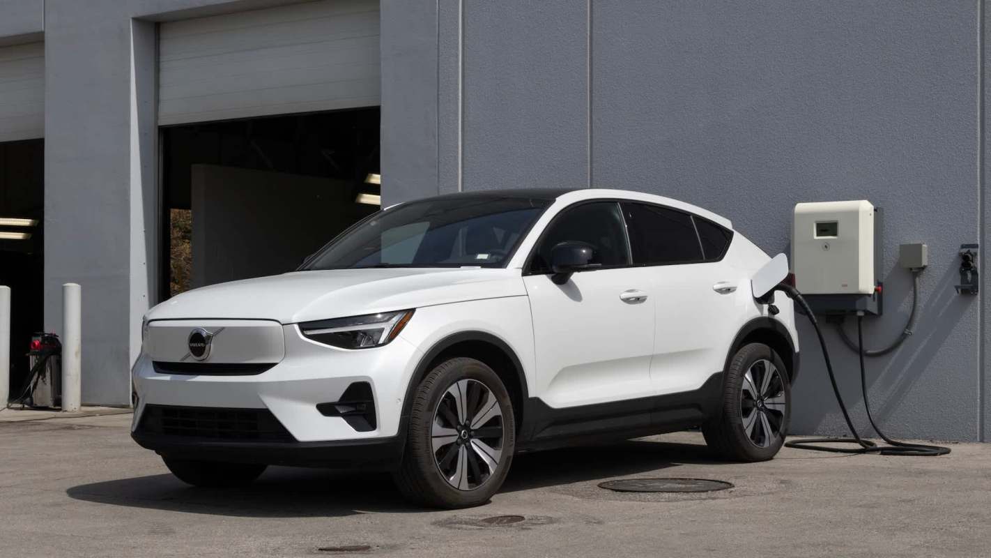A white electric SUV parked at a charging station outside a building.