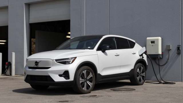 A white electric SUV parked at a charging station outside a building.